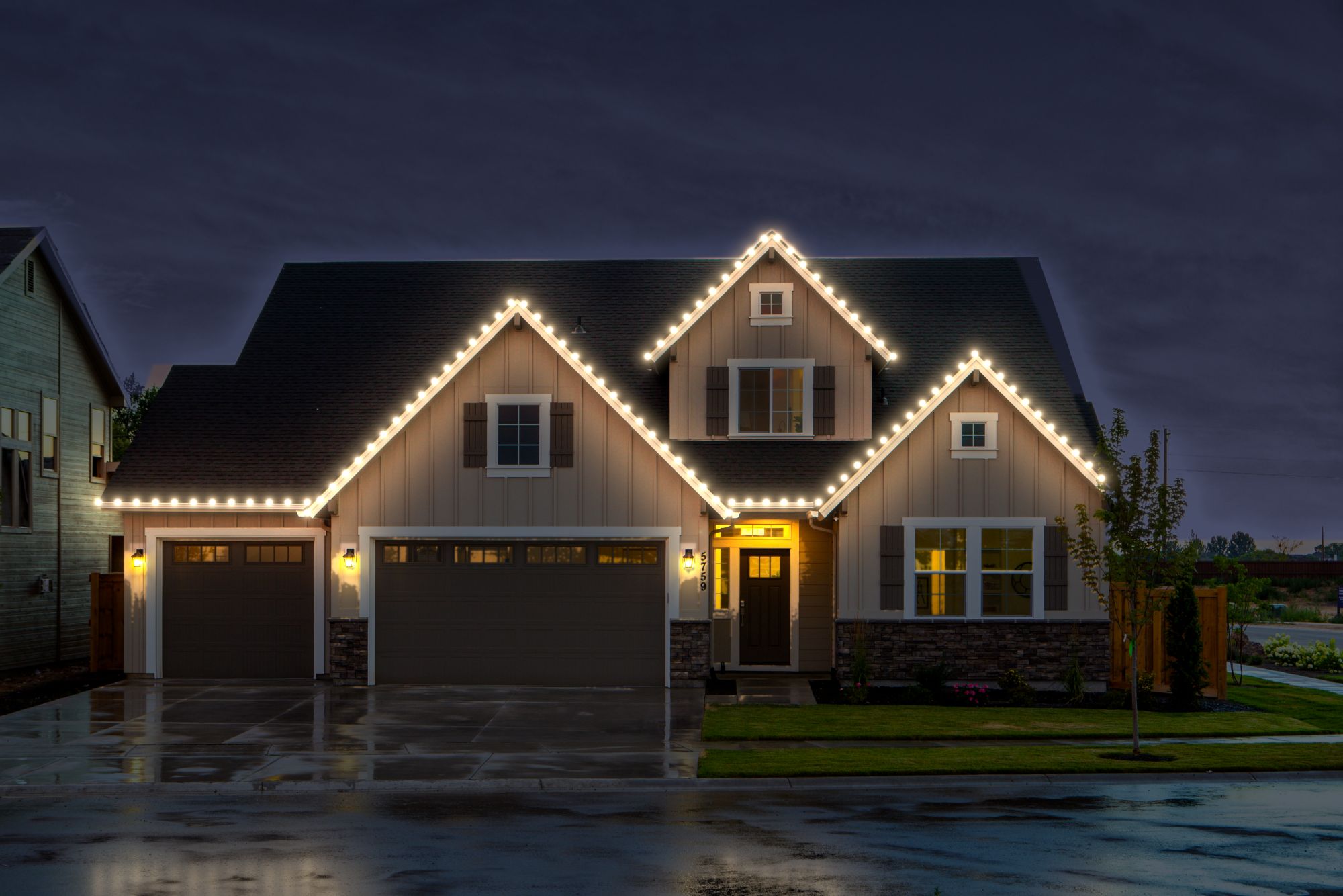 A two story house at night with warm white C9 bulbs along every eave and gable, shown as a design preview