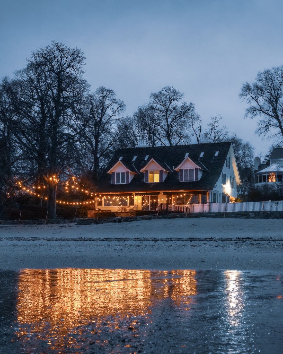 Warm white bulbs running the eave line of a house at dusk
