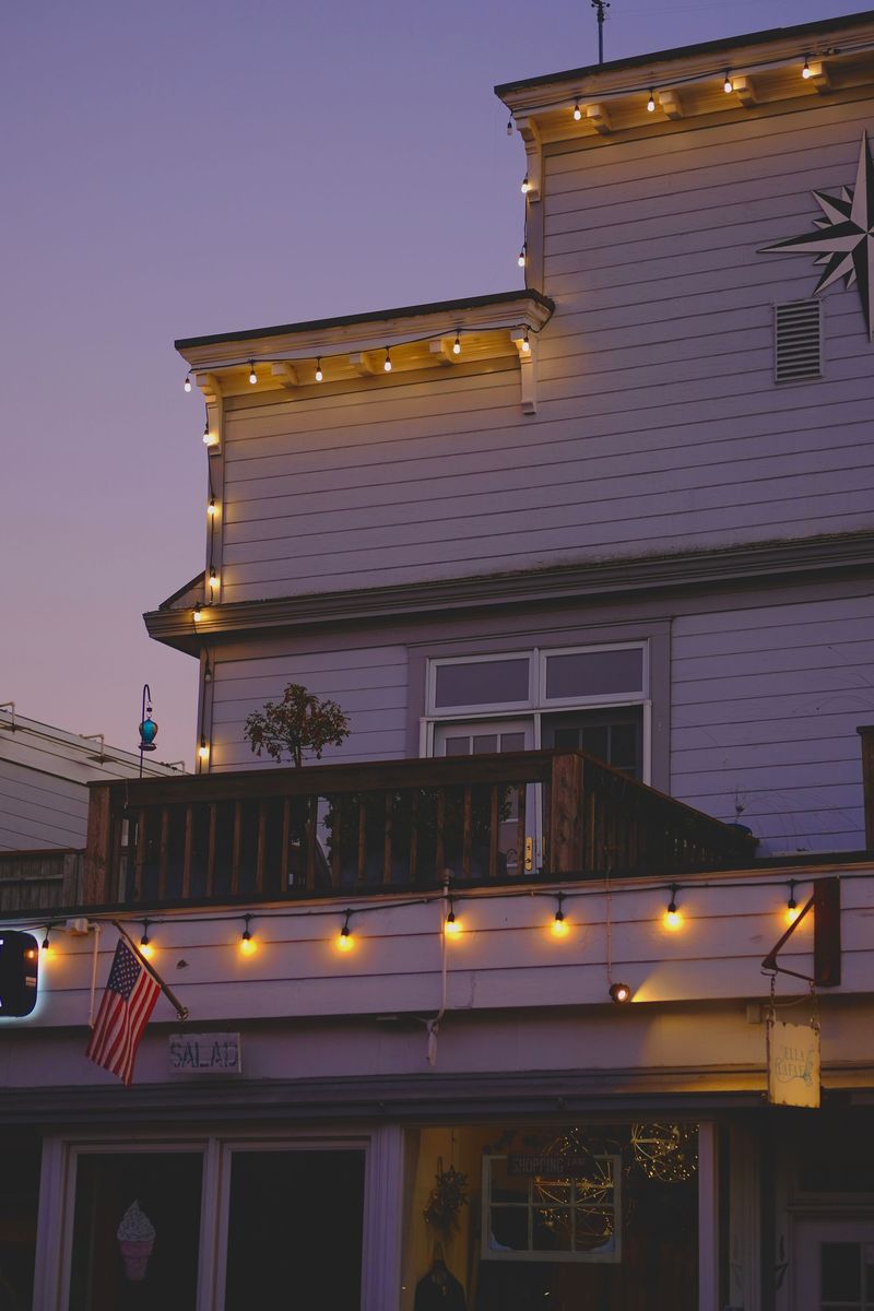 Warm white bulbs running the eave and gable line of a house at dusk, evenly spaced