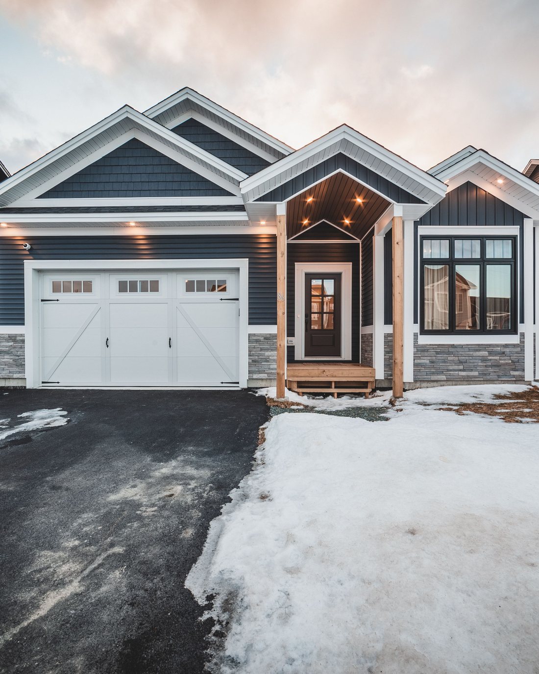 A newer house at dusk in snow with the roofline run in warm white
