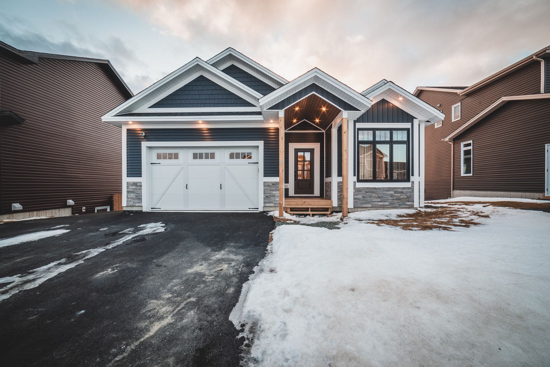 A newer house at dusk in snow with the roofline run in warm white