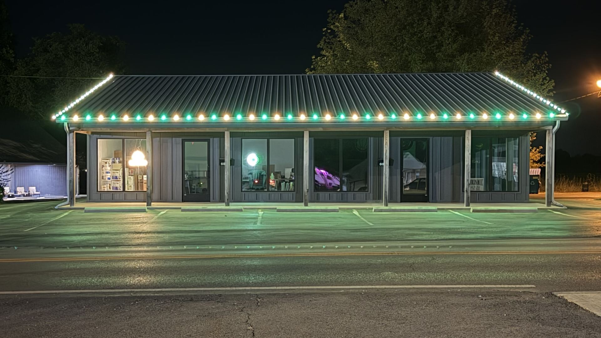 Our office in Sheridan at night, lit along the roofline in green and warm white