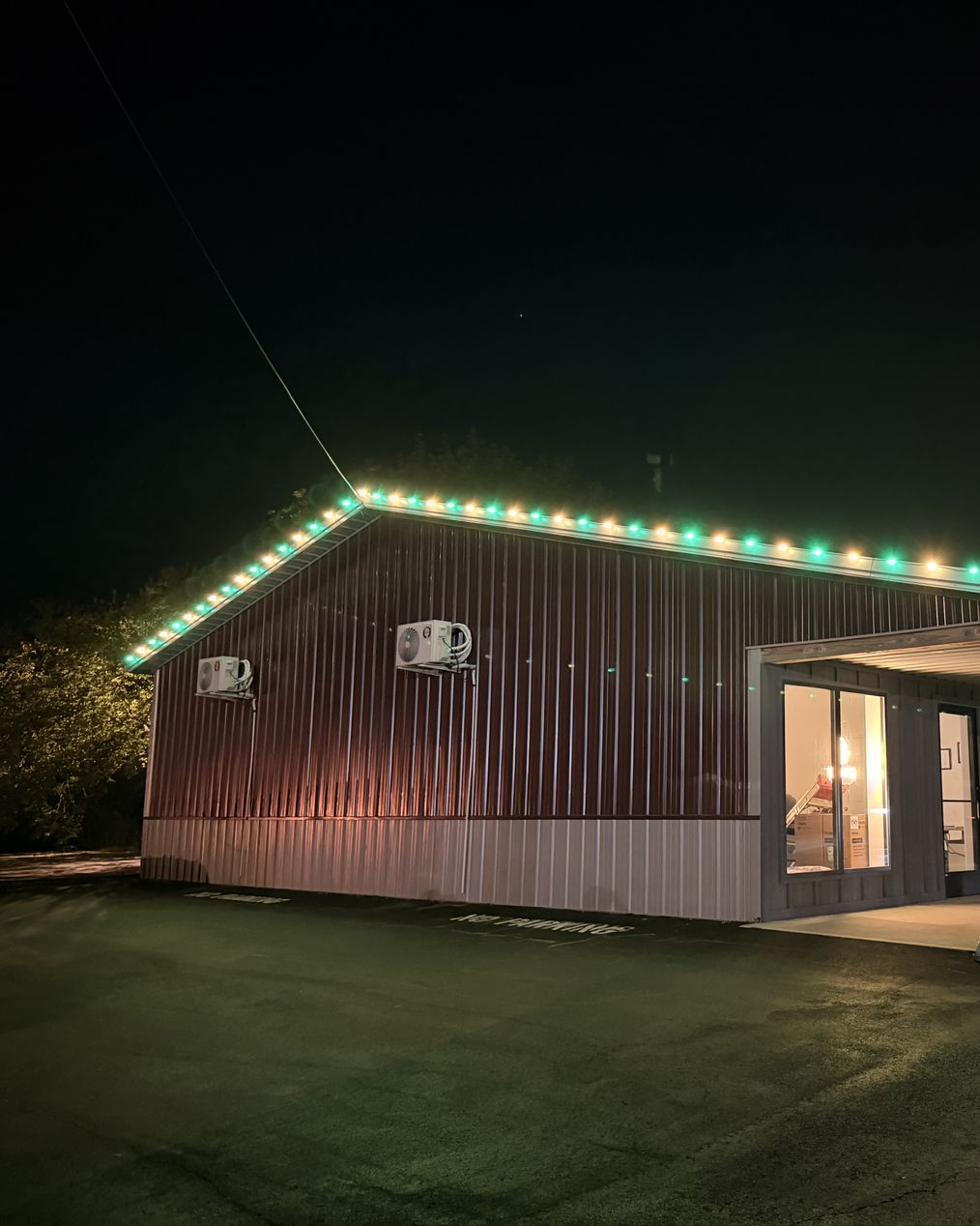 Our office in Sheridan at night, with green and warm white bulbs along the eave and up the gable end